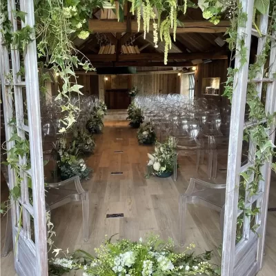 Salle de mariage fleurie avec des arrangements floraux le long de l'allée et une arche décorée par un fleuriste événementiel